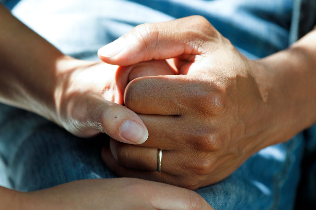 A younger hand gently holding an older loved one’s hand